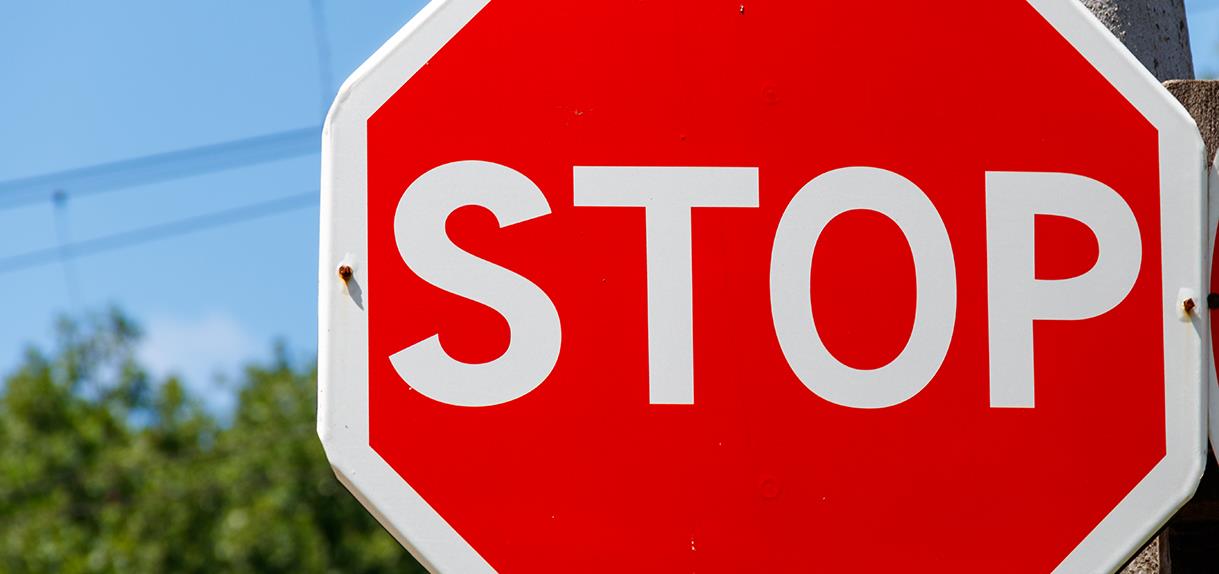 Närbild på stopp-skylt med röd bakgrund och vita bokstäver